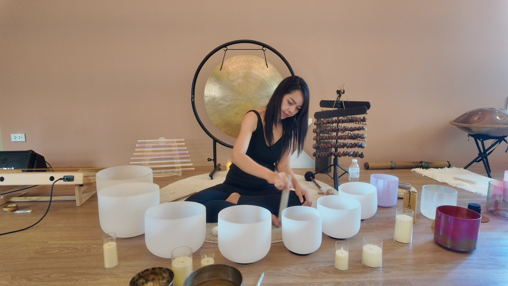 Practitioner learning to play crystal singing bowls